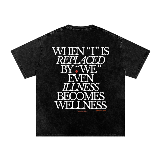 Black t-shirt with 'When I is replaced by We even illness becomes wellness', a Malcolm X quote, and the Holistic+Kin logo on a white background